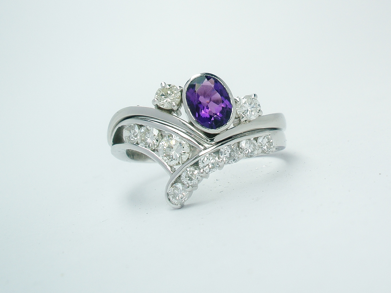 A 3 stone amethyst and round brilliant cut diamond wishbone style ring mounted in platinum and shaped to fit in with a 9 stone diamond wishbone ring.