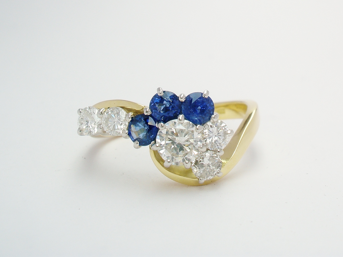 An 8 stone round brilliant cut and sapphire cross-over style ring mounted in 18ct yellow gold and platinum.