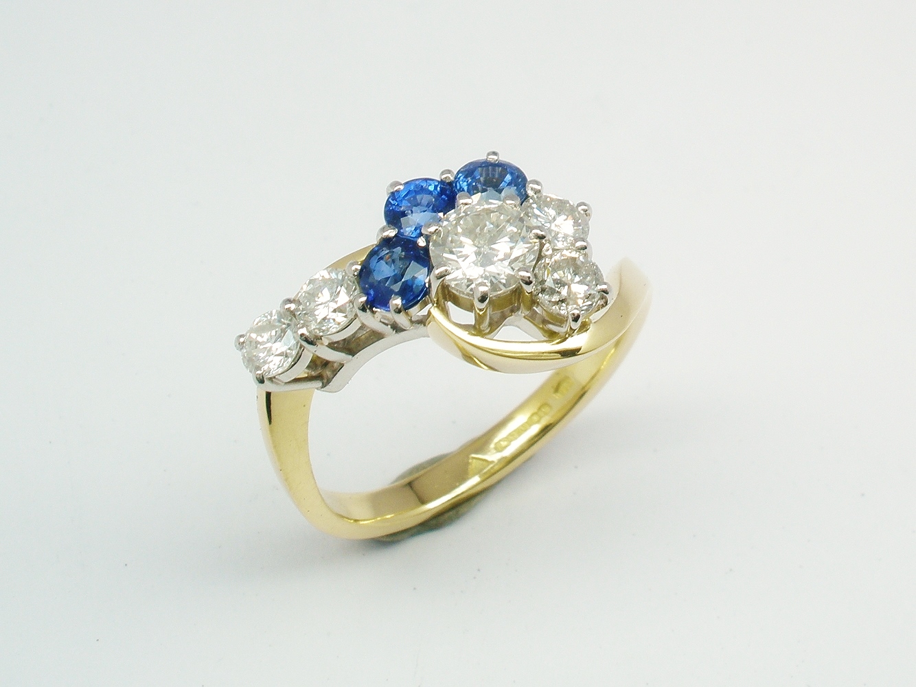 An 8 stone round brilliant cut and sapphire cross-over style ring mounted in 18ct yellow gold and platinum.