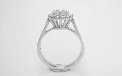 A 13 stone round brilliant cut diamond cluster with channel set round brilliant cut diamond shoulders.