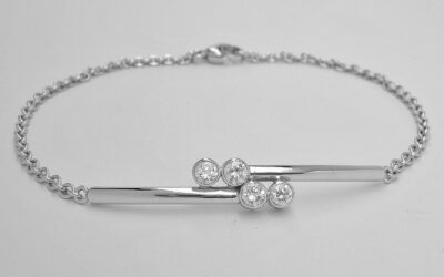 A 4 stone rub-over set round brilliant cut diamond cross-over style bracelet with centre solid panel mounted in platinum with platinum chain.