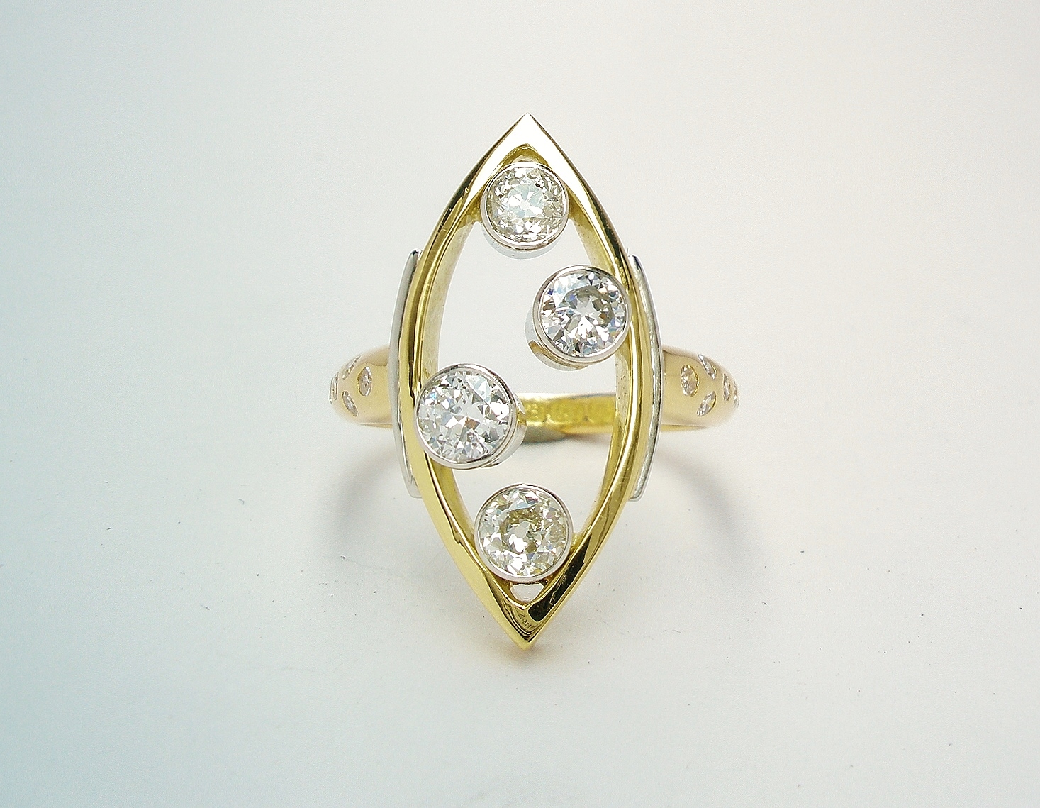 A 4 stone Victorian cut and round brilliant cut diamond marquise shaped ring mounted in 18ct. yellow gold and platinum with small brilliant cut round diamonds flush set in the shoulders.