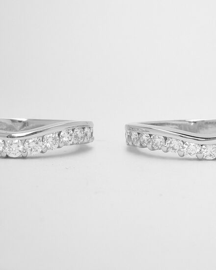 A pair of 13 stone, part channel set round brilliant cut diamond rings mounted in platinum and shaped to fit around a single stone engagement ring with diamond shoulders.