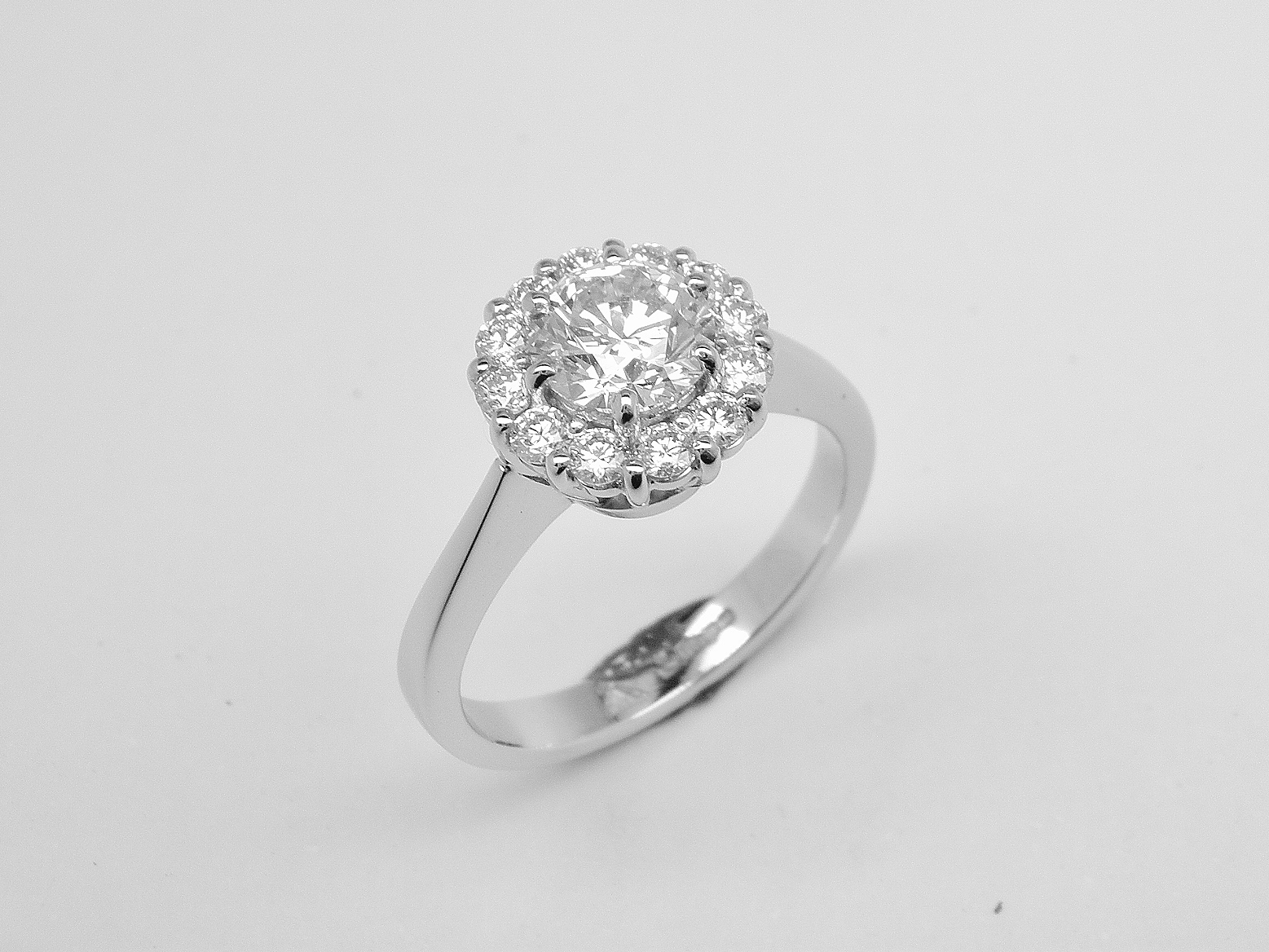 A 13 stone round brilliant cut diamond cluster mounted in platinum with a solid knife edged shoulder shank.