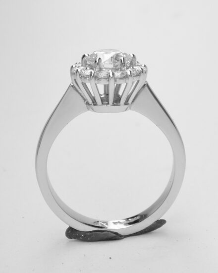 A 13 stone round brilliant cut diamond cluster mounted in platinum with a solid knife edged shoulder shank.