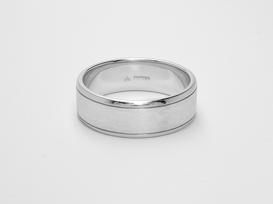 A gents 7mm broad platinum ring with lines cut 1.2mm i from both edges with polished edges and brushed finish centre.