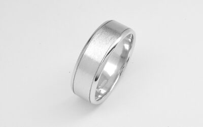 A gents 7mm broad platinum ring with lines cut 1.2mm i from both edges with polished edges and brushed finish centre.