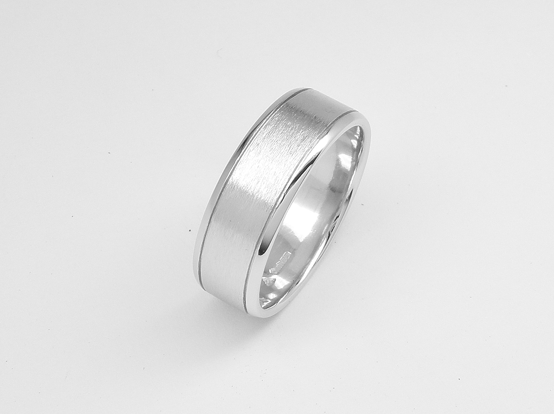 A gents 7mm broad platinum ring with lines cut 1.2mm i from both edges with polished edges and brushed finish centre.