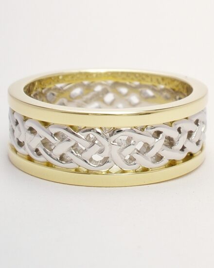 A 7.5mm broad platinum & 18ct. yellow gold ring. The centre 4.5mm platinum band carved in a Celtic pattern and edged on both sides with a 1.5mm broad 18ct yellow gold wires.