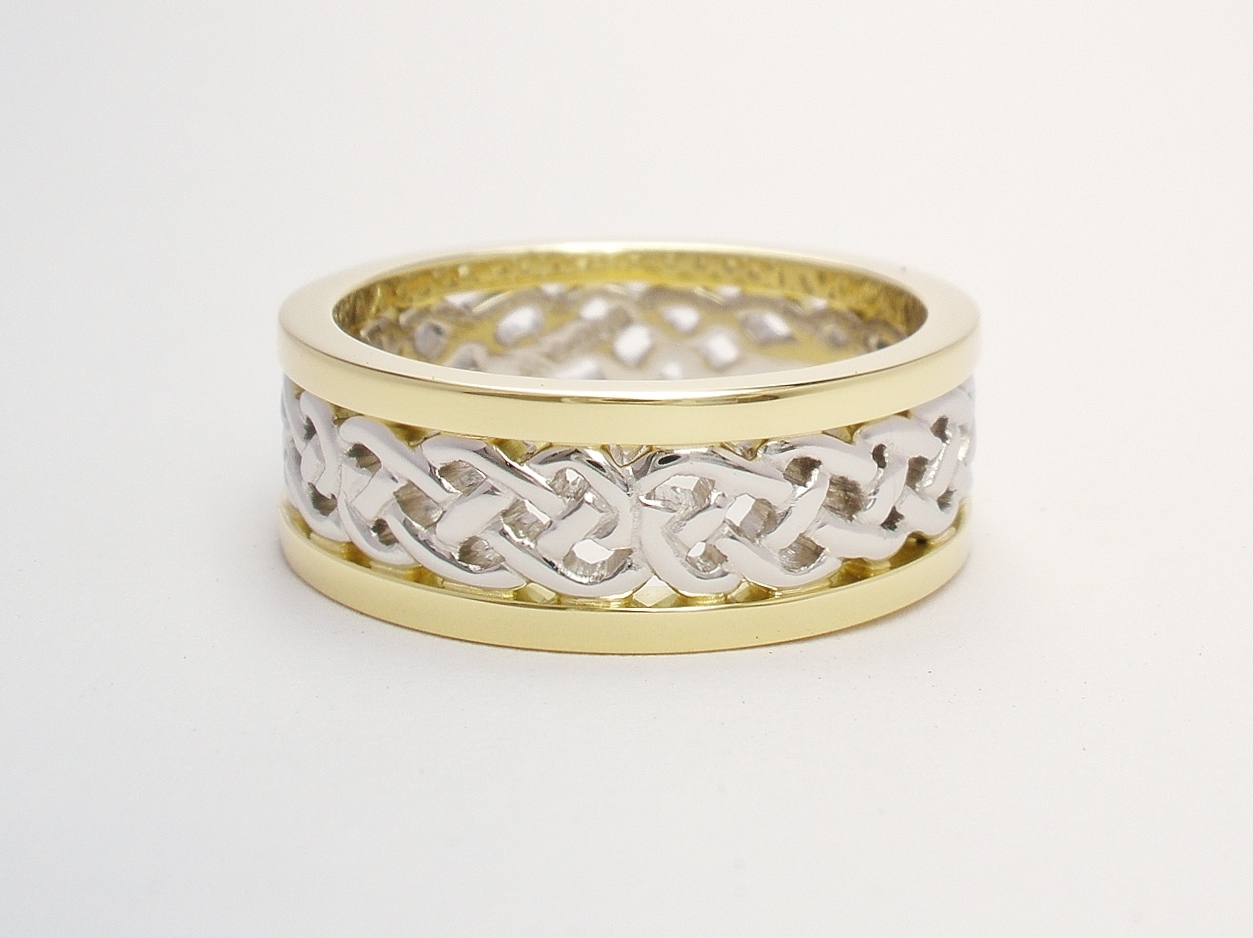 A 7.5mm broad platinum & 18ct. yellow gold ring. The centre 4.5mm platinum band carved in a Celtic pattern and edged on both sides with a 1.5mm broad 18ct yellow gold wires.