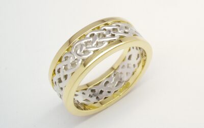 A 7.5mm broad platinum & 18ct. yellow gold ring. The centre 4.5mm platinum band carved in a Celtic pattern and edged on both sides with a 1.5mm broad 18ct yellow gold wires.