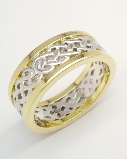 A 7.5mm broad platinum & 18ct. yellow gold ring. The centre 4.5mm platinum band carved in a Celtic pattern and edged on both sides with a 1.5mm broad 18ct yellow gold wires.