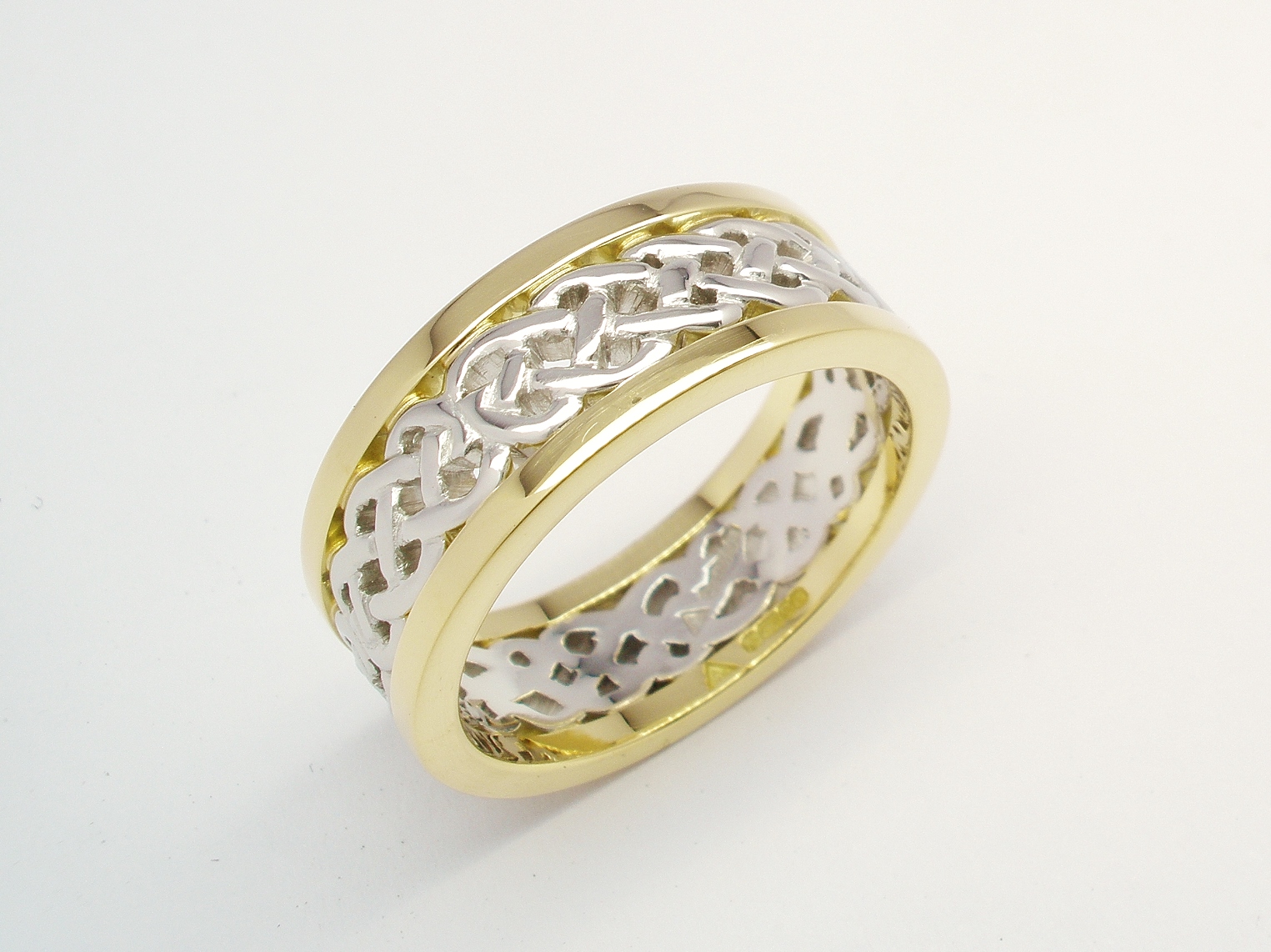 A 7.5mm broad platinum & 18ct. yellow gold ring. The centre 4.5mm platinum band carved in a Celtic pattern and edged on both sides with a 1.5mm broad 18ct yellow gold wires.