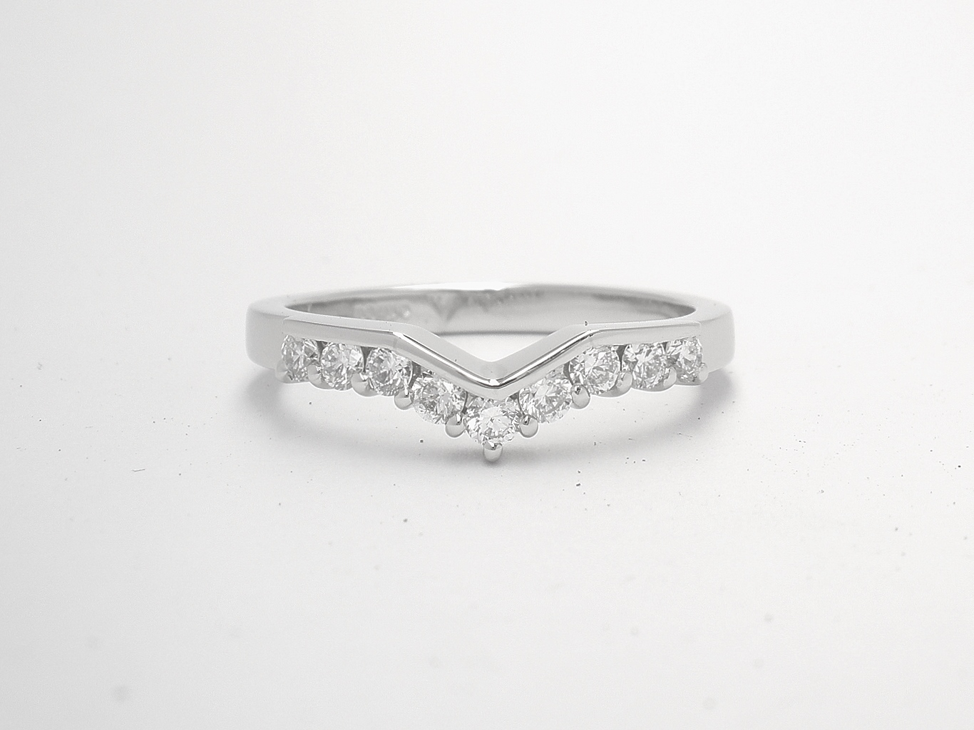 A 9 stone part channel set round brilliant cut diamond slight wishbone shaped ring shaped to fit with a 3 stone diamond ring mounted in platinum.