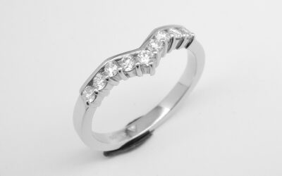 A 9 stone part channel set round brilliant cut diamond slight wishbone shaped ring shaped to fit with a 3 stone diamond ring mounted in platinum.