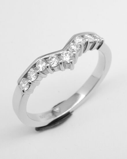 A 9 stone part channel set round brilliant cut diamond slight wishbone shaped ring shaped to fit with a 3 stone diamond ring mounted in platinum.