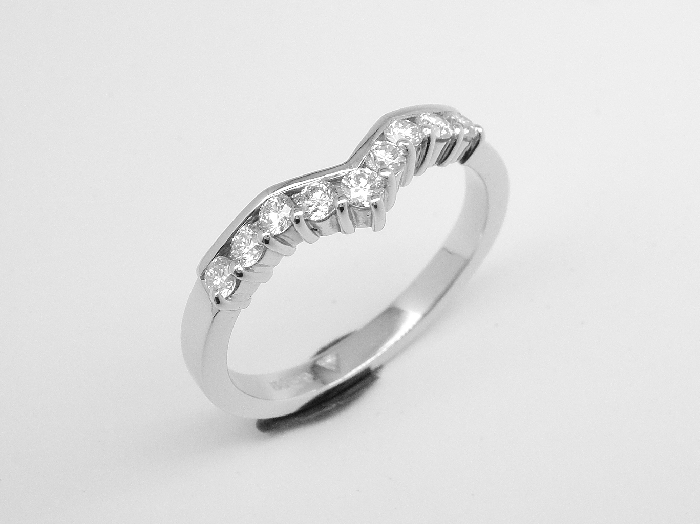 A 9 stone part channel set round brilliant cut diamond slight wishbone shaped ring shaped to fit with a 3 stone diamond ring mounted in platinum.