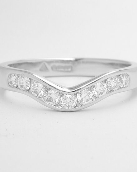 A 9 stone round brilliant cut diamond channel set ring mounted in platinum and shaped to fit with a single stone marquise diamond ring.