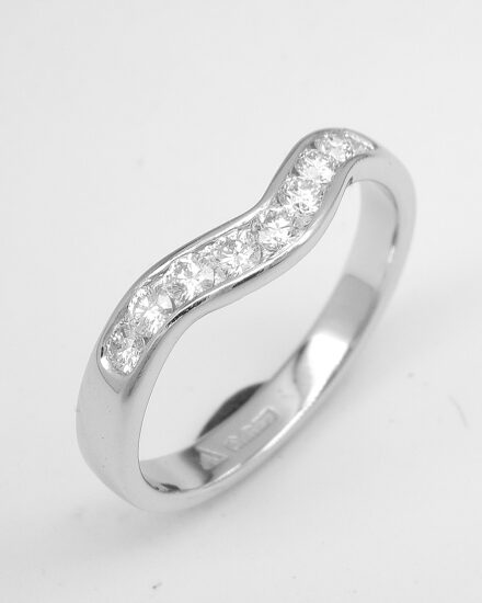 A 9 stone round brilliant cut diamond channel set ring mounted in platinum and shaped to fit with a single stone marquise diamond ring.