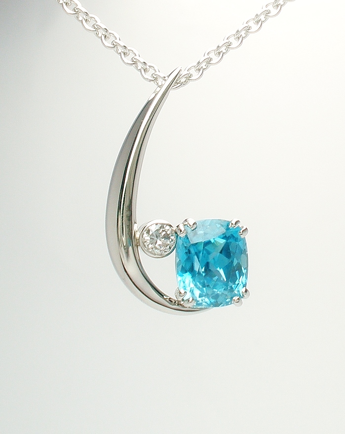 A 2 stone rectangular cushion shaped blue zircon and round brilliant cut diamond pendant mounted in 9ct. white gold and platinum.