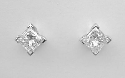 A pair of single stone princess cut diamond ear studs mounted in platinum with 'Guardian' comfort fit fittings.