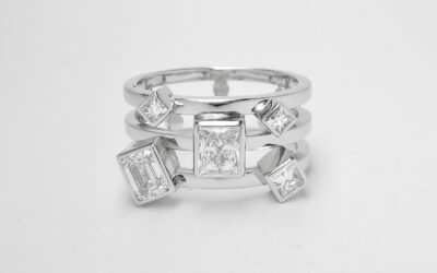 A 5 stone princess and emerald cut diamond triple banded ring mounted in platinum.