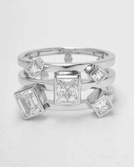 A 5 stone princess and emerald cut diamond triple banded ring mounted in platinum.