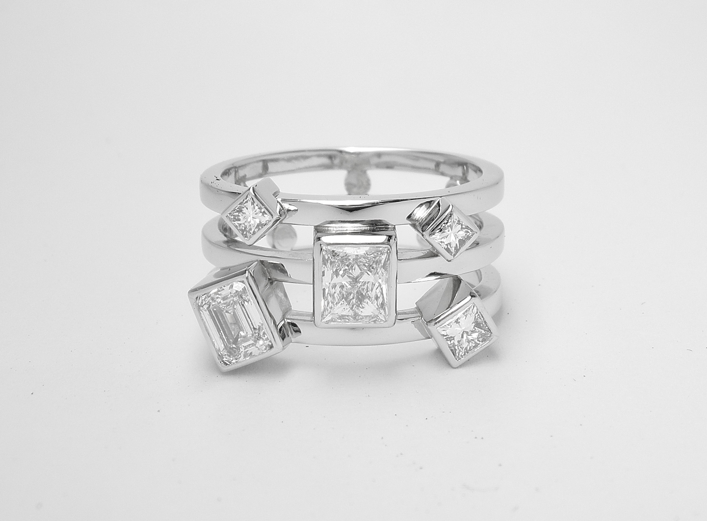 A 5 stone princess and emerald cut diamond triple banded ring mounted in platinum.