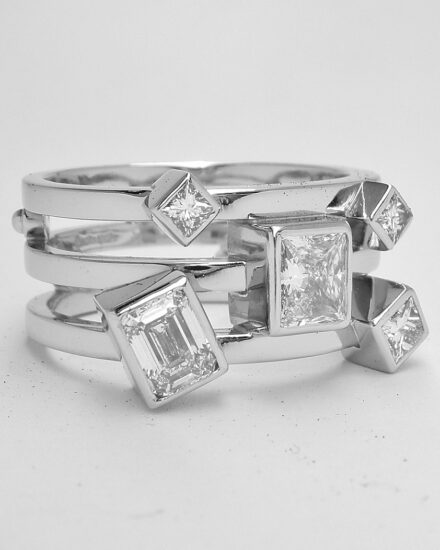 A 5 stone princess and emerald cut diamond triple banded ring mounted in platinum.