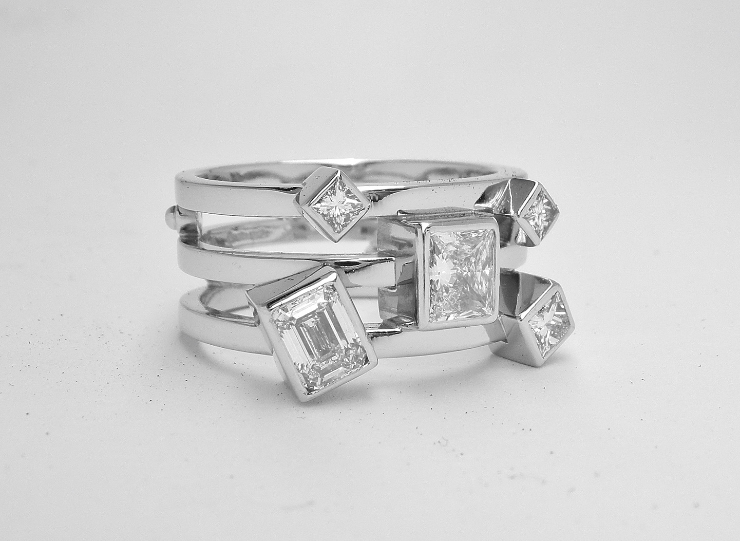 A 5 stone princess and emerald cut diamond triple banded ring mounted in platinum.