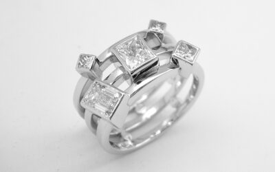 A 5 stone princess and emerald cut diamond triple banded ring mounted in platinum.