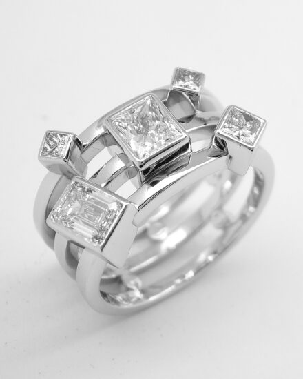 A 5 stone princess and emerald cut diamond triple banded ring mounted in platinum.