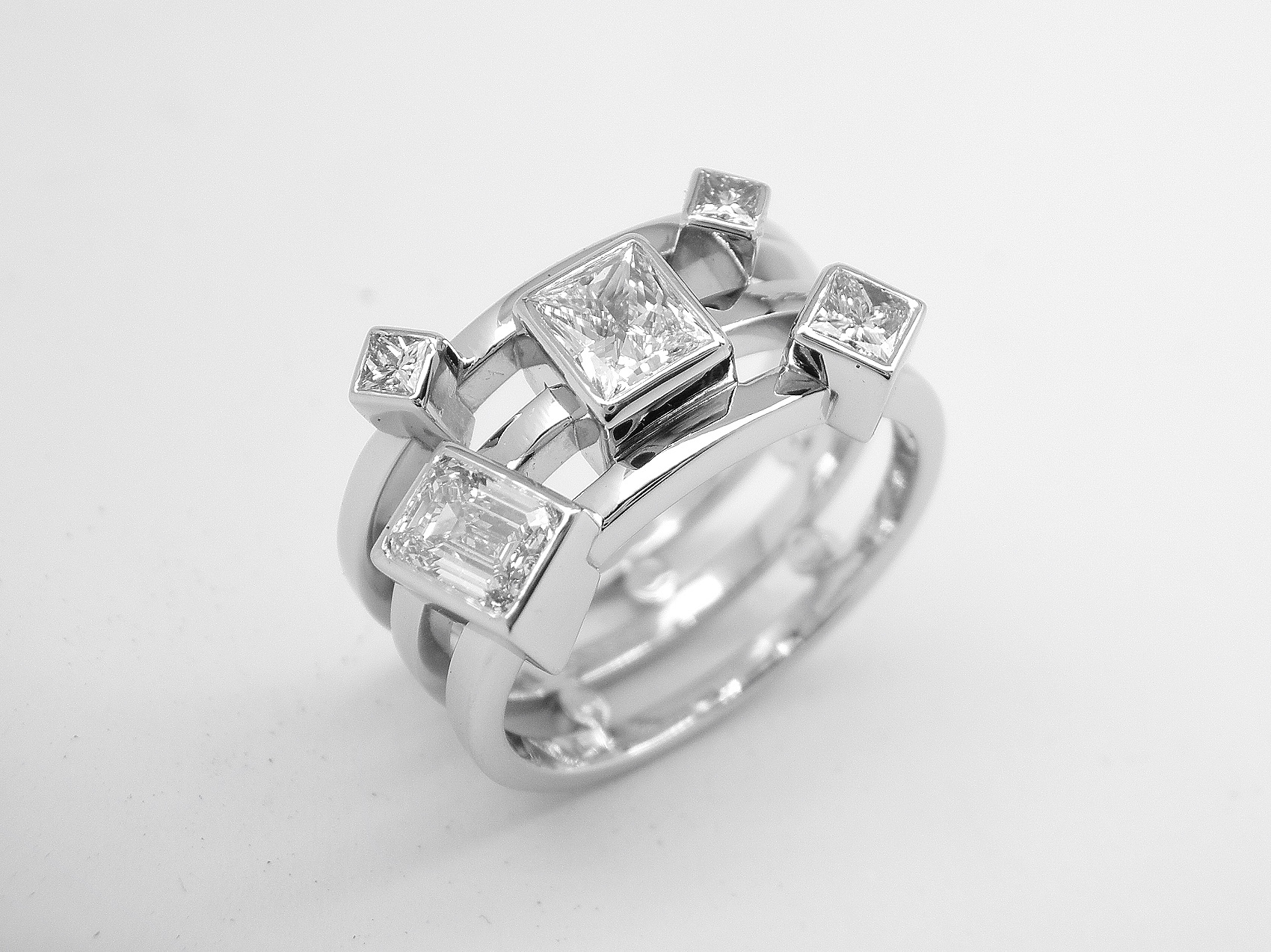 A 5 stone princess and emerald cut diamond triple banded ring mounted in platinum.