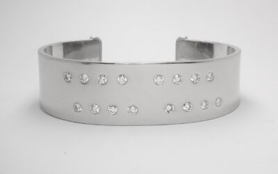 A 20mm broad heavy sectioned platinum torque bangle flush set with 16 round brilliant cut diamonds.