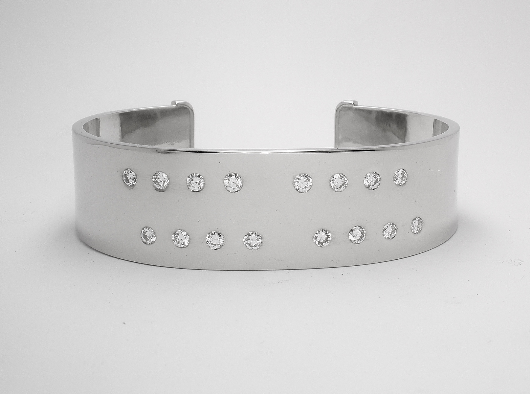 A 20mm broad heavy sectioned platinum torque bangle flush set with 16 round brilliant cut diamonds.