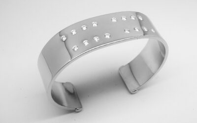 A 20mm broad heavy sectioned platinum torque bangle flush set with 16 round brilliant cut diamonds.