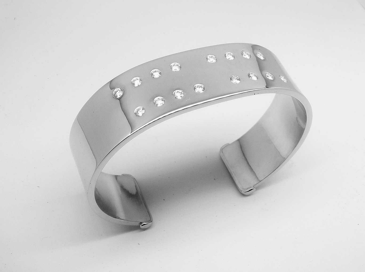 A 20mm broad heavy sectioned platinum torque bangle flush set with 16 round brilliant cut diamonds.