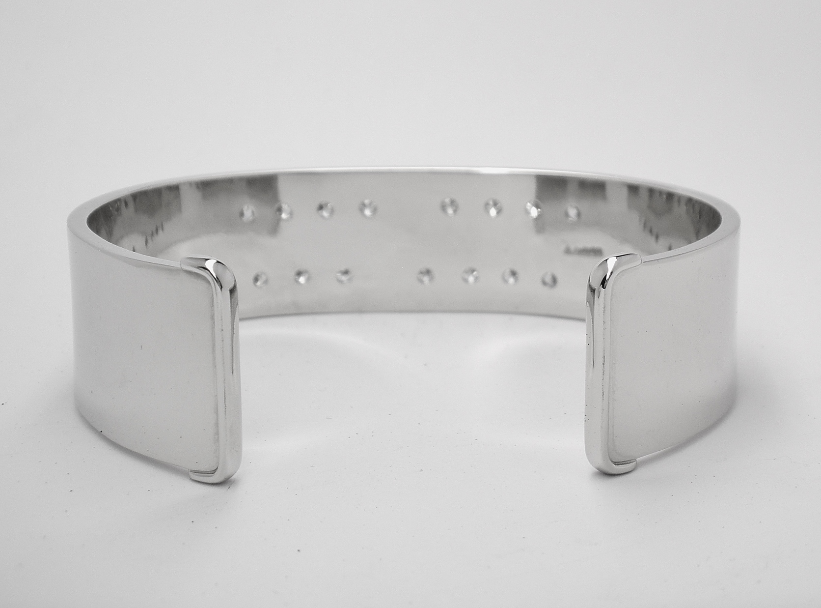 A 20mm broad heavy sectioned platinum torque bangle flush set with 16 round brilliant cut diamonds.