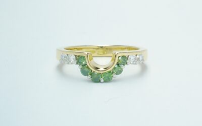 A 10 stone part channel set round brilliant cut green and white diamond wedding ring shaped to fit around a single stone oval diamond engagement ring.