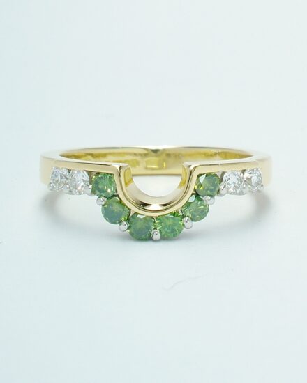 A 10 stone part channel set round brilliant cut green and white diamond wedding ring shaped to fit around a single stone oval diamond engagement ring.