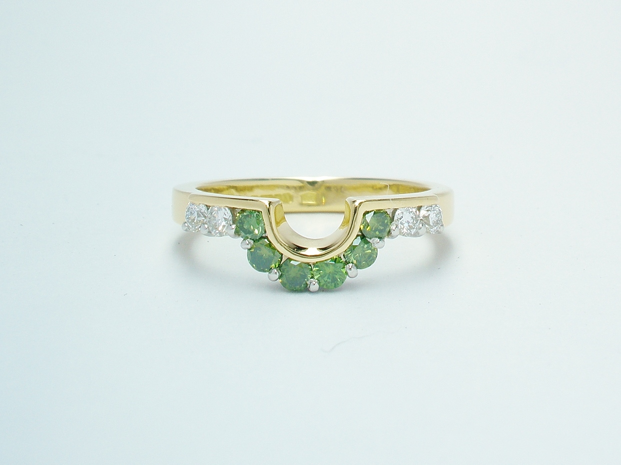 A 10 stone part channel set round brilliant cut green and white diamond wedding ring shaped to fit around a single stone oval diamond engagement ring.