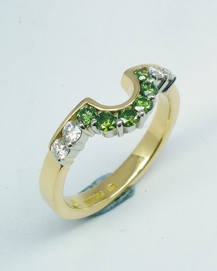 A 10 stone part channel set round brilliant cut green and white diamond wedding ring shaped to fit around a single stone oval diamond engagement ring.