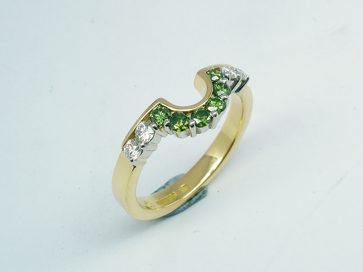 A 10 stone part channel set round brilliant cut green and white diamond wedding ring shaped to fit around a single stone oval diamond engagement ring.