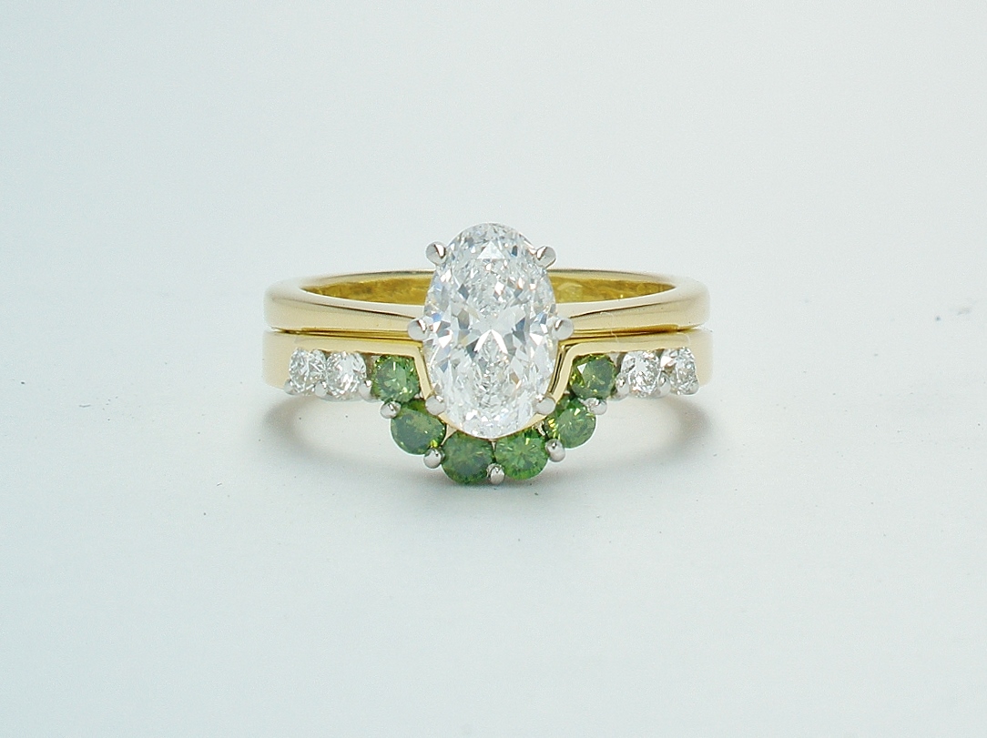 A 10 stone part channel set round brilliant cut green and white diamond wedding ring shaped to fit around a single stone oval diamond engagement ring.
