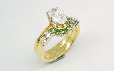 A 10 stone part channel set round brilliant cut green and white diamond wedding ring shaped to fit around a single stone oval diamond engagement ring.