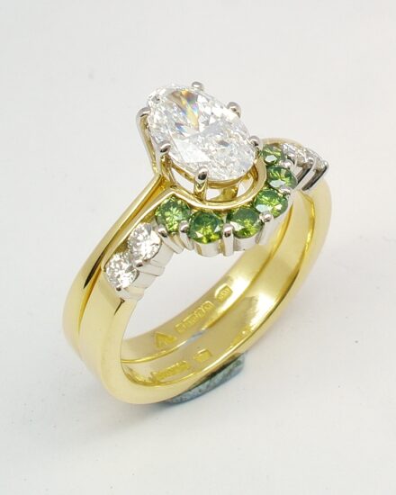 A 10 stone part channel set round brilliant cut green and white diamond wedding ring shaped to fit around a single stone oval diamond engagement ring.