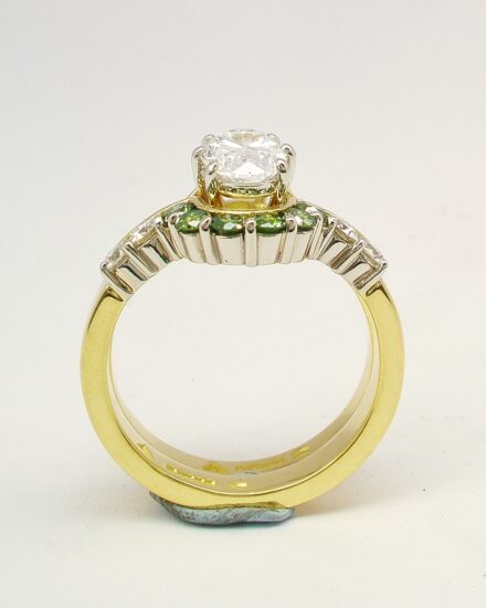 A 10 stone part channel set round brilliant cut green and white diamond wedding ring shaped to fit around a single stone oval diamond engagement ring.