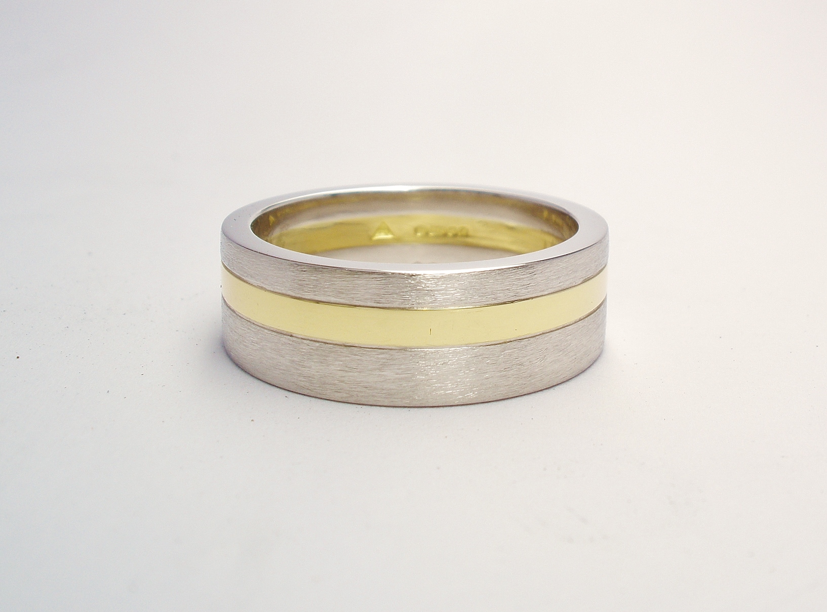 A 6mm broad heavy flat sectioned platinum and 18ct. yellow gold gents wedding ring.