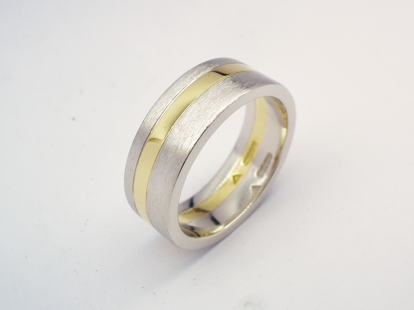 A 6mm broad heavy flat sectioned platinum and 18ct. yellow gold gents wedding ring.