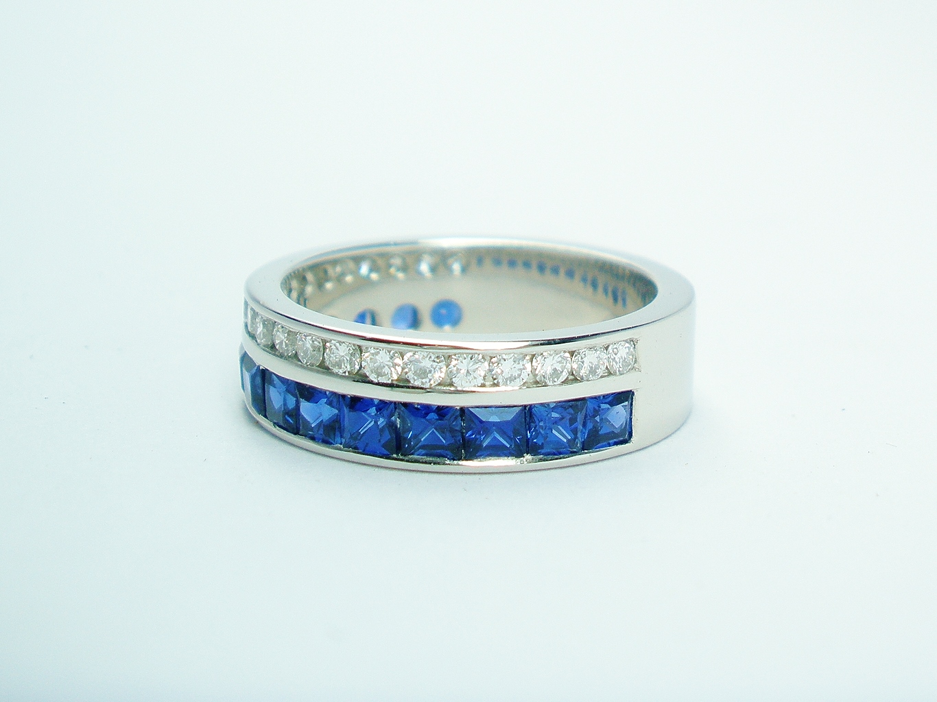 A 37 stone square cut sapphire and round brilliant cut diamond ring channel set in a 5mm broad flat heavy sectioned platinum band.